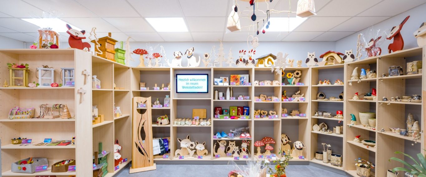 Werkstattladen mit allen Produkten Der Laden. Ein heller Raum mit Holzregalen, gefüllt mit Artikeln aus Holz, Filz und Keramik.