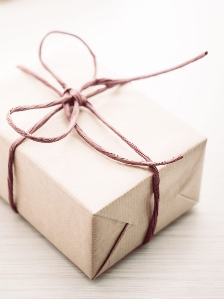 Geschenke Geschenkideen. Geschenkverpackungen in braunem Papier mit rotem Band, auf hellem Hintergrund.